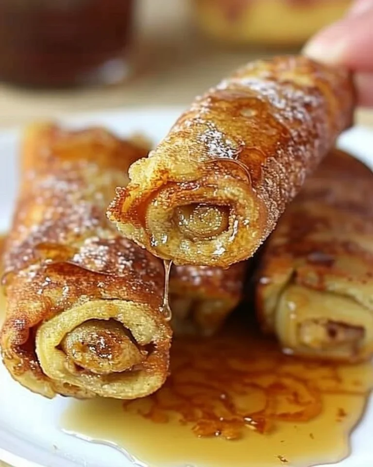 Plate of delicious French Toast Rollups served with syrup and berries.