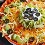 Delicious seven-layer taco dip served in a festive dish for fall gatherings